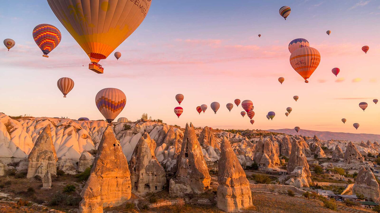 Dozens of colourful hot air balloons floating over Cappadocia’s fairy chimneys at sunrise